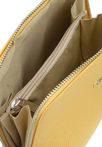 Portafoglio in pelle gialla con un esterno testurizzato, svariati scomparti e chiusura con zip in metallo argentato. L'interno è in tessuto beige.