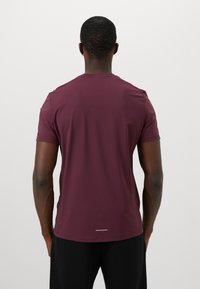 Bordeaux kortermet t-skjorte med glatt tekstur, rund hals og en reflekterende stripe langs kanten, med en tettsittende design på baksiden.