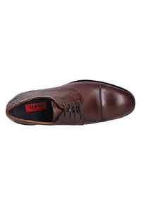 Brown leather dress shoe with smooth texture, round toe, stitched details, and six eyelets for laces. Inside, red logo visible.