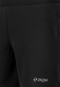 Zwarte sportshorts gemaakt van glad, lichtgewicht stof. Heeft een subtiele witte logo in de rechteronderhoek.