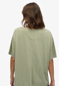 Kortærmet, afslappet fit t-shirt i lys olivengrøn. Blødt, tekstureret stof med rund halsudskæring og synlige sømdetaljer på bagsiden.