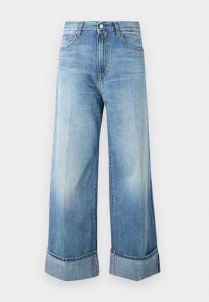 Jean en denim bleu clair à jambes larges, taille haute, bouton et fermeture éclair à l’avant, cinq poches et larges revers roulés.