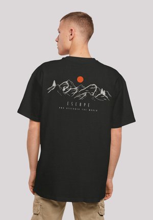 Black cotton t-shirt featuring a graphic of mountains and a red sun on the back, with the text "ESCAPE AND DISCOVER THE WORLD" below.