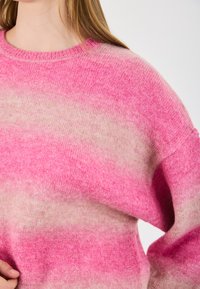 Maglione con gradiente rosa e lavorazione a maglia testurizzata, con scollatura rotonda e vestibilità morbida. La tonalità passa da un rosa brillante a un beige tenue.