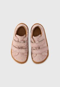 Chaussures en daim roses avec deux sangles Velcro. Présentent des motifs d'étoiles en rose et violet. Semelles en caoutchouc marron, design à bout arrondi.