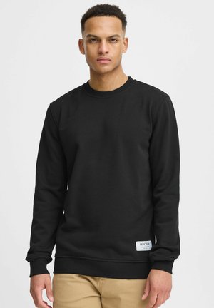 Zwarte sweatshirt met lange mouwen en een ronde hals, gemaakt van een gladde stof. Kenmerkt zich door een klein label op de onderste rechtermorgen.