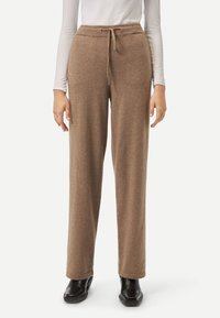 Bruna, mjuka sweatpants i tyg med dragsko i midjan, rak ben-design och subtil textur. Betoning på en avslappnad passform.