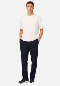Camiseta blanca de manga corta combinada con pantalones azul marino. La camiseta tiene un escote redondo; los pantalones son ajustados y tienen un acabado suave.