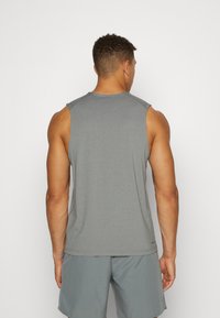 Graues ärmelloses Sportshirt mit strukturierter Oberfläche, Rundhalsausschnitt und lockerer Passform, getragen mit grauen Shorts.