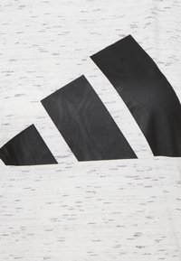 Formes géométriques noires disposées en diagonale sur un fond de tissu blanc avec une texture noire légèrement tachetée.
