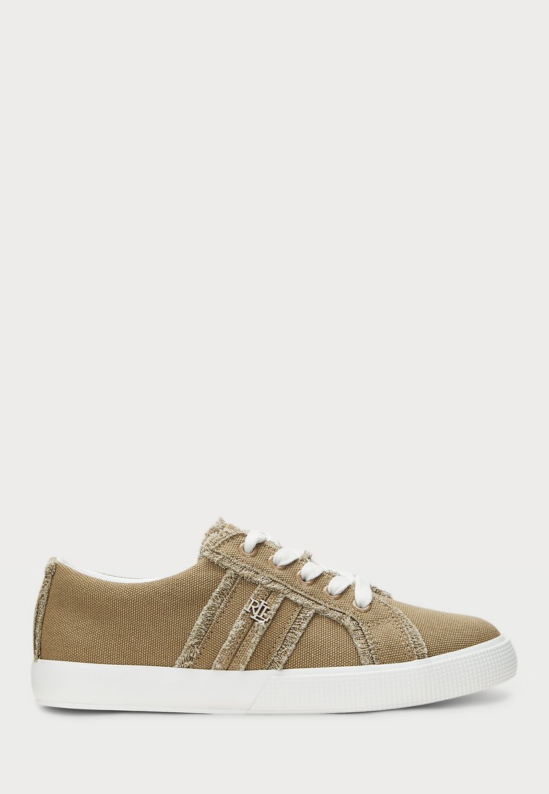 Beige lerret sneakers med hvite gummisåler, med frynsete kanter, seks hull, og fremtredende logo detaljer på siden.