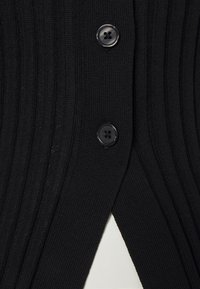 Černý žebrovaný pletený cardigan s dvěma černými knoflíky, s texturovanou látkou a V-čkovým výstřihem vpředu.