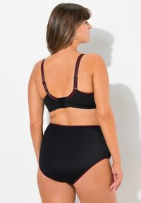 Černá plavková souprava s texturovaným designem, nastavitelnými ramínky a červenými akcenty. Kalhotky s vysokým pasem poskytují plné krytí.