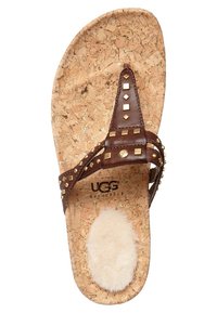 Infradito in pelle marrone con accenti borchiati, sottopiede in sughero e morbida fodera in pelle di pecora bianca. Presenta una superficie texture e il marchio UGG.