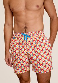 Rode zwemshorts met een geometrisch patroon in blauw, geel en wit. Voorzien van een elastische tailleband en een bijpassend trekkoord.