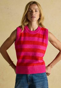 Ärmelloser gestrickter Pullover in pinken und roten Streifen, mit einem gerippten Halsausschnitt und Saum. Weicher Stoff, lässiger Stil, kombiniert mit Denim-Shorts.