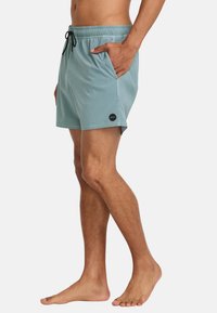 Lichtblauwe zwemshorts van sneldrogende stof, met een elastische tailleband met trekkoord en zakken aan beide zijden.