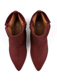 Stivali alla caviglia in suede bordeaux con punta appuntita e interno in morbida pelle tan. Presentano una texture soffice e una vestibilità aderente attorno alla caviglia.
