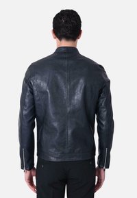 Giacca in pelle nera con design con zip, caratterizzata da un colletto rialzato, forma aderente e zip argentate sulle maniche. Finitura testurizzata.