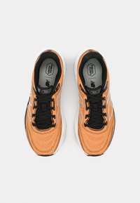 Oranje sport schoenen met zwarte accenten, voorzien van een bovenwerk van mesh, veters, een gewatteerde kraag en een witte, gevoerde zool. "Fresh Foam" merknaam aan de binnenkant.