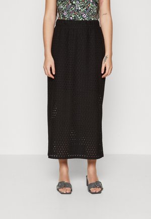 Svart midiskjørt i åpen mesh-design med fleksibel midje. Båret med grå slip-on sandaler med spenne-detalj.