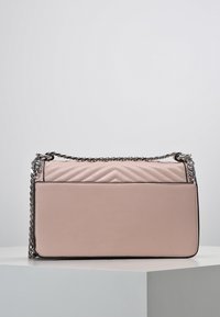 Borsa a mano in pelle rosa con un design a chevron a trapunta sulla parte frontale, tracolla in catena argentata e una superficie liscia. Forma rettangolare.