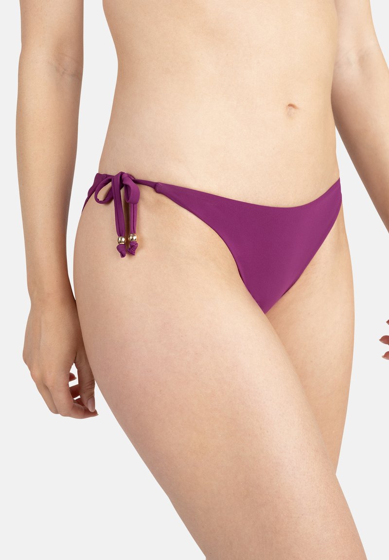 Bas de bikini violet avec des côtés à nouer réglables et des perles dorées en accent. Fabriqué en matériau lisse, il offre une couverture minimale et un design épuré.