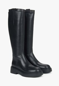 Zwarte leren kniehoge laarzen met een gladde afwerking, stevige rubberen zool en subtiele stikdetails. Voorzien van een trekband aan de bovenkant.