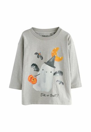 T-shirt gris à manches longues avec un graphisme de fantôme portant un chapeau noir, une lune orange et des citrouilles, avec le texte "des bonbons ou un sort ?" en dessous.