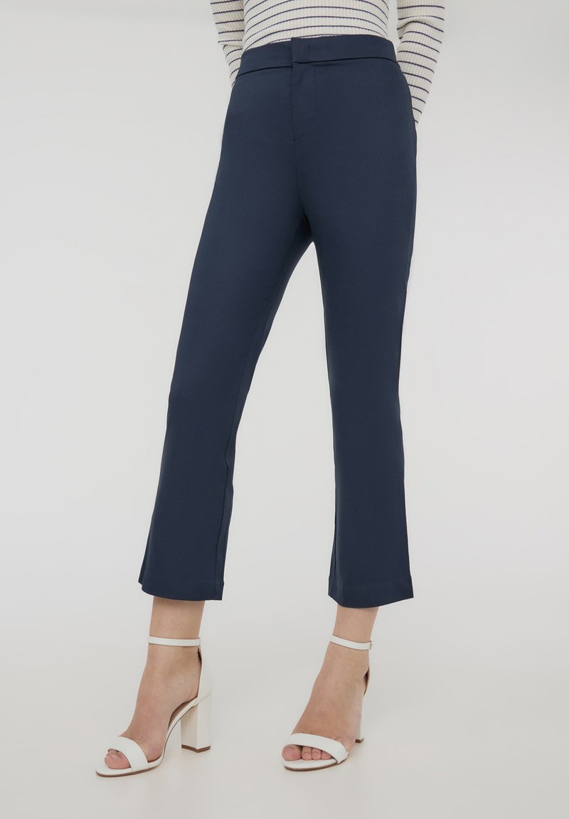 Pantaloni blu navy dal taglio su misura, con vita media, gambe dritte e orlo pulito. Il tessuto è liscio con una leggera elasticità.