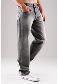 Graue Denim-Jeans mit geradem Schnitt, fünf Taschen, Steppnähte und abgenutztem Look. Kombiniert mit weißen Sneakers.