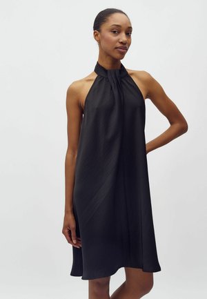 Schwarzes Trägerkleid aus leichtem, fließendem Stoff. Mit einem plissierten Ausschnitt und einem lässigen Schnitt, der bis zum Knie reicht.