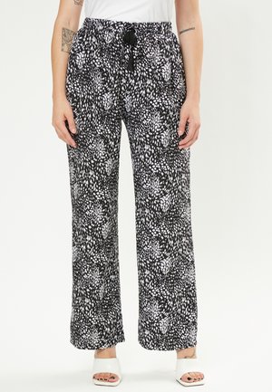 Pantalons larges à motifs noir et blanc avec une taille élastique et un cordon de serrage ajustable. Tissu léger avec une coupe ample et sans poches.