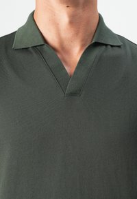 Mørkegrøn polo skjorte med V-halskrave, lavet af et blødt, tekstureret stof, med korte ærmer og et rent, moderne design.