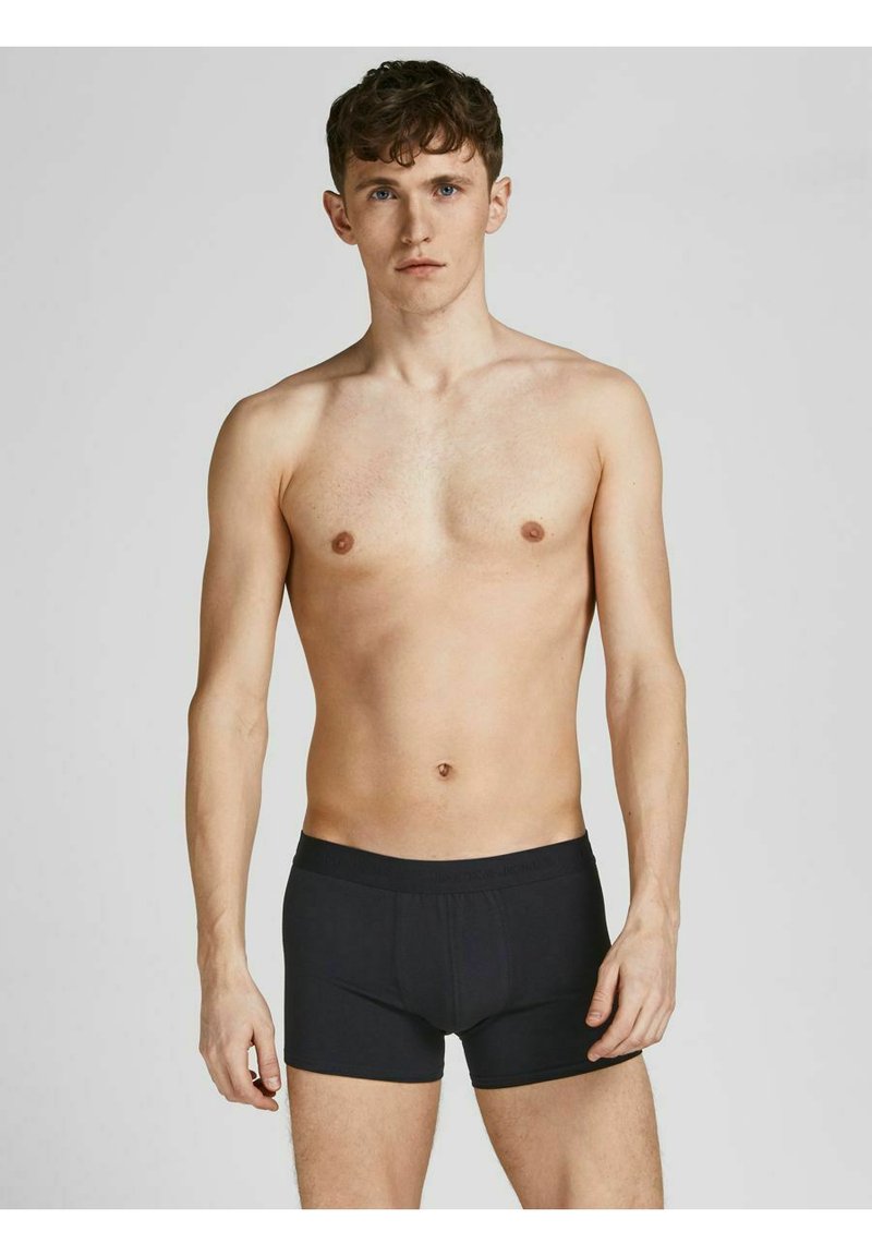 Schwarze Boxershorts aus elastischem Stoff, mit einem weichen Bund und enganliegendem Schnitt. Das abgebildete Modell steht aufrecht, die Arme an den Seiten.