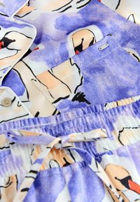 Könnyű, több színű szövet, mely folyékony absztrakt mintákat tartalmaz lila, őszibarack és fekete árnyalatokban. Rugalmas derékrésszel és húzózsinórral ellátva.