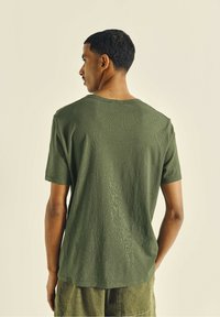 Olive green cotton t-shirt with a crew neckline, short sleeves, and a relaxed fit; features a subtle textured pattern along the fabric.