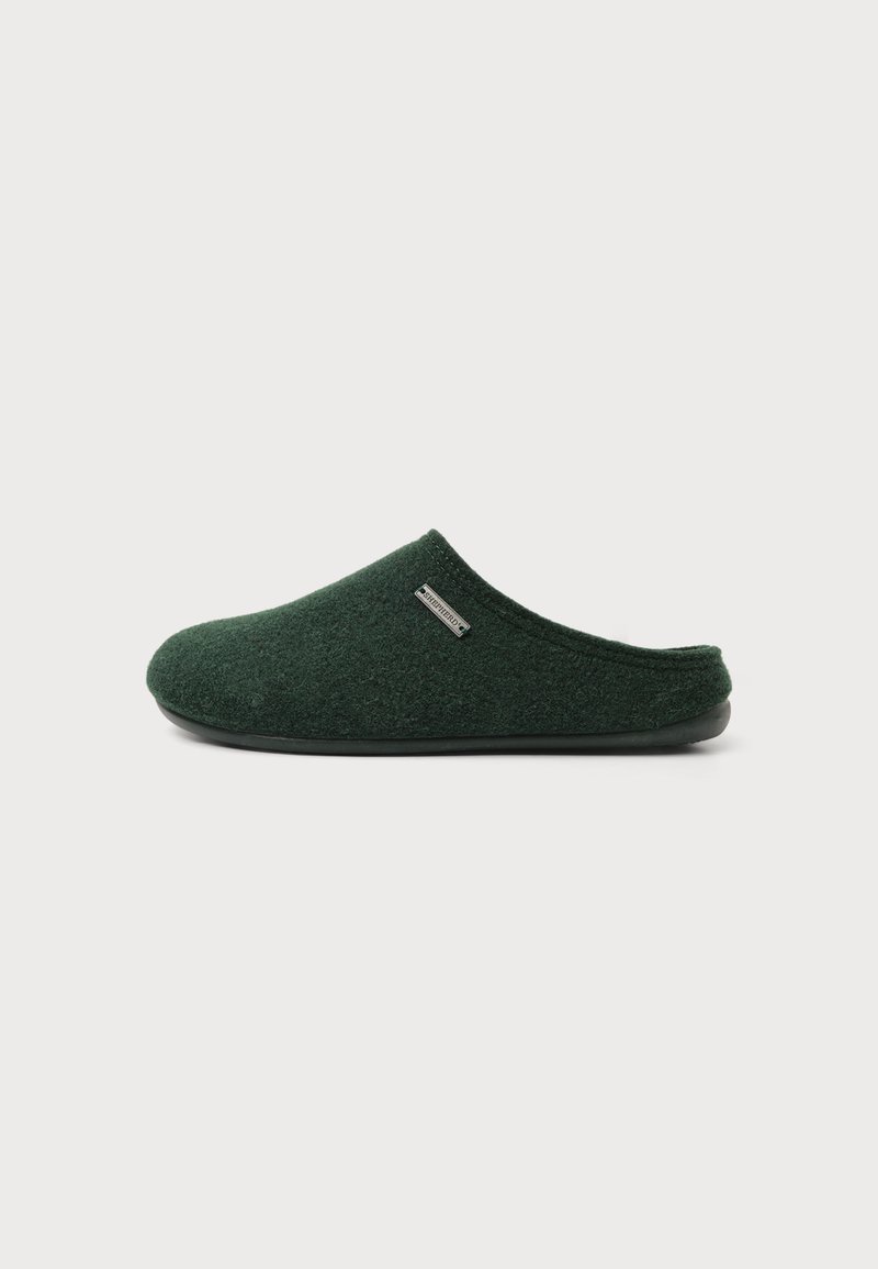 Chausson vert foncé à enfiler, fermé à l’avant, avec une tige en tissu doux et une semelle noire sur un fond clair uni.