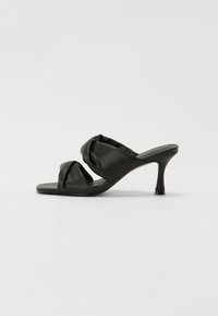 Sandali neri con tacco, caratterizzati da morbidi cinturini annodati, punta aperta e un elegante tacco stiletto. Realizzati in materiale liscio con un design minimalista.