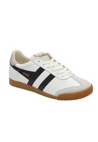 Zapatillas de cuero blancas con rayas negras, puntera de ante y suela de goma. Logo dorado en la lengüeta y en el lateral.