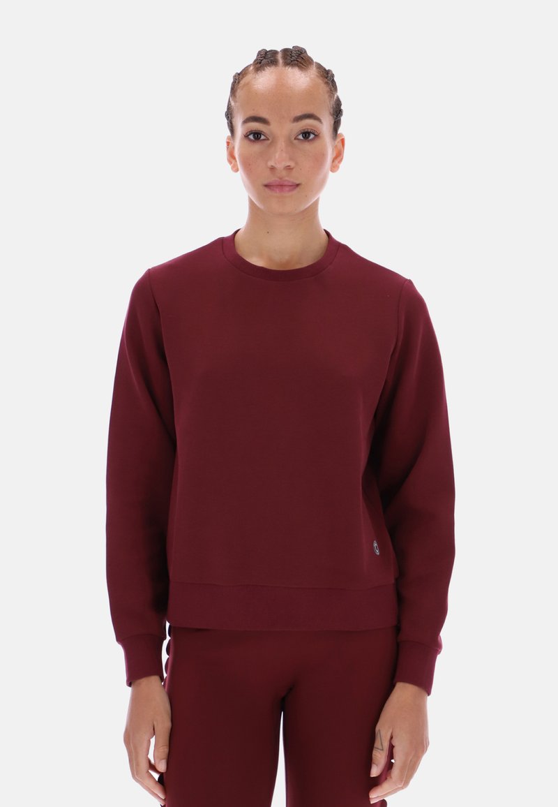 Burgundowy sweatshirt z okrągłym dekoltem, wykonany z miękkiego materiału, z długimi rękawami, luźnym krojem, ściągaczami oraz małym akcentem logo.