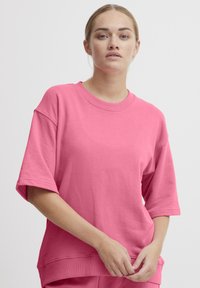 Lyserød oversized sweatshirt i bomuldsblandingsmateriale. Har brede korte ærmer, rund halsudskæring og ribbet kant. Glat struktur.