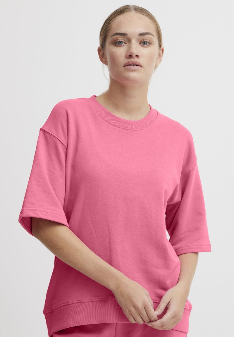 Lyserød oversized sweatshirt i bomuldsblandingsmateriale. Har brede korte ærmer, rund halsudskæring og ribbet kant. Glat struktur.