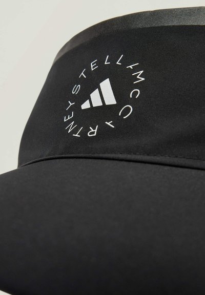 Crna kapa od tkanine s zakrivljenim vizirjem, koja sadrži kružni bijeli logo i tri vertikalne pruge kao istaknuti dizajnerski detalj.