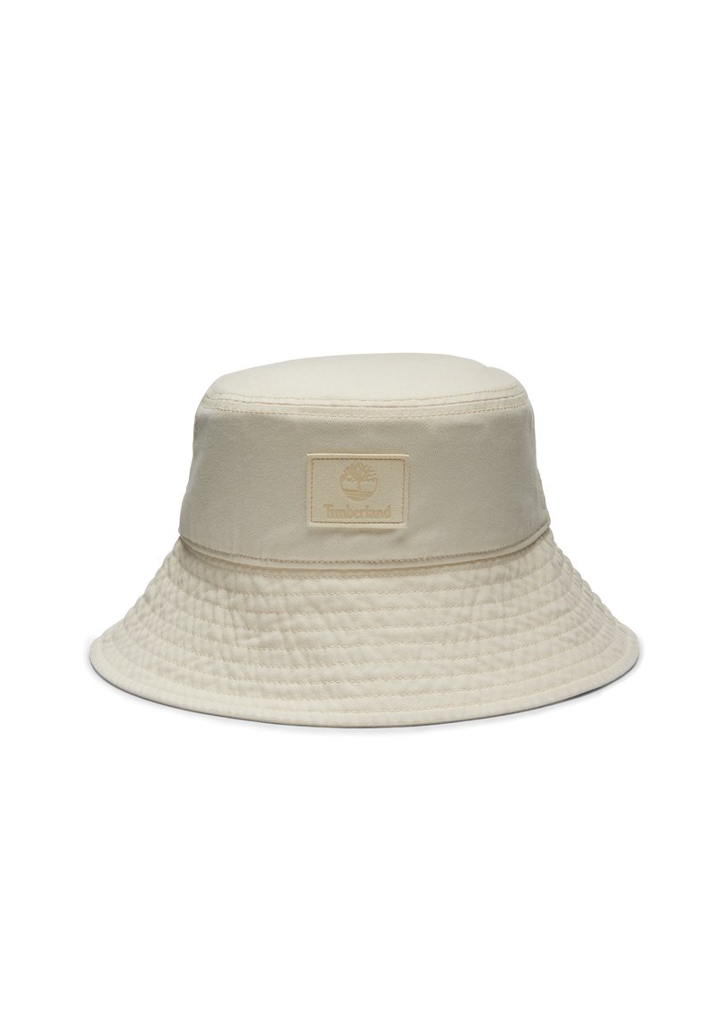 Beige buckethat lavet af bomuld med en tekstureret overflade. Har et syet bånd og et kvadratisk logopatch på fronten.