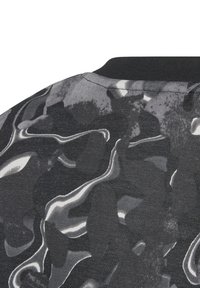 Tela de patrón en negro y gris con un diseño ondulado, que presenta una superficie texturizada y un cuello acanalado negro sólido.