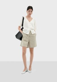 Witte linnen blouse met knopen, beige op maat gemaakte shorts, zilveren ballerina's en een zwarte schoudertas. Eenvoudig ontwerp met een ontspannen pasvorm.