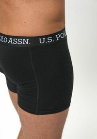 Črne bombažne bokserice z širokim elastičnim pasom, na katerem je bel napis "U.S. POLO ASSN." Gladka tekstura in prilegajoča zasnova.