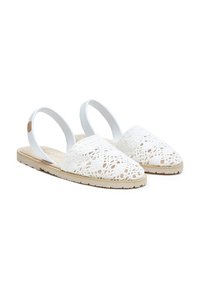 Sandalias planas de ganchillo blancas con punta cerrada, tira elástica en la parte posterior y suelas de goma beige, exhibidas sobre fondo blanco.