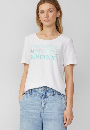 T-shirt en coton blanc à manches courtes avec "FUNTASTIC" imprimé en bleu clair sur le devant. Porté avec un short en denim bleu clair.